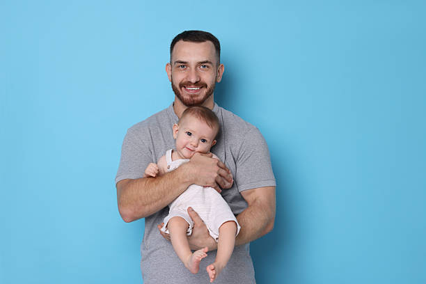 istock Father with his cute baby on light blue background 2222404334