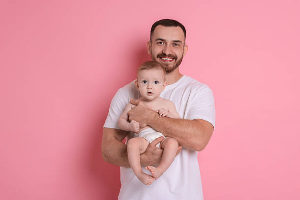 istock Father with his cute baby on pink background 2222404336