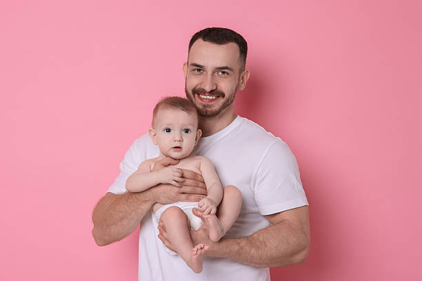 istock Father with his cute baby on pink background 2222404355