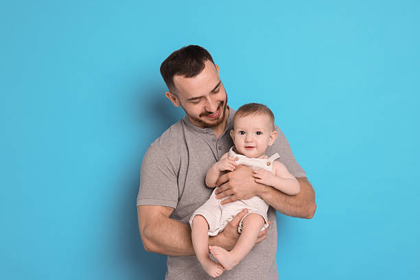 istock Father with his cute baby on light blue background 2222404363