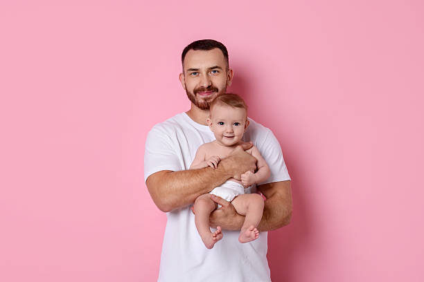 istock Father with his cute baby on pink background 2222404370
