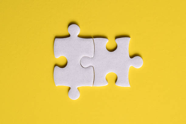 istock Two white puzzle pieces on a yellow background 2222405428