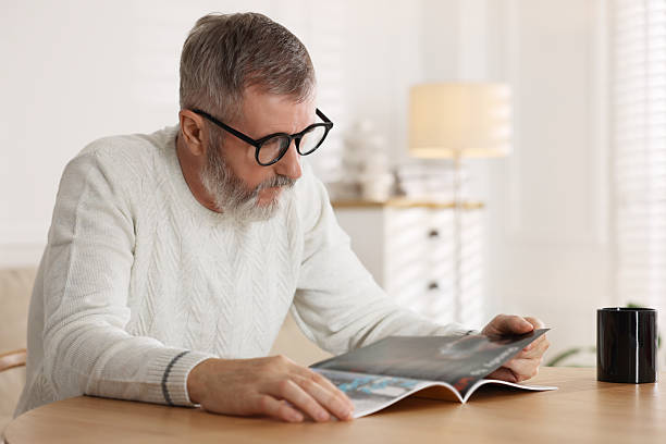istock Senior man reading magazine at table indoors 2222405730