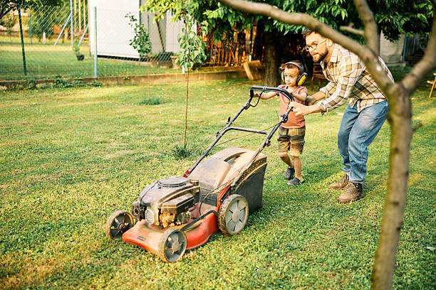 istock Father and son mowing lawn together in backyard. 2222408169