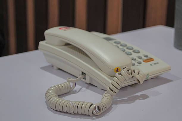 istock Classic white landline telephone with curly cord resting on a table surface 2222408268