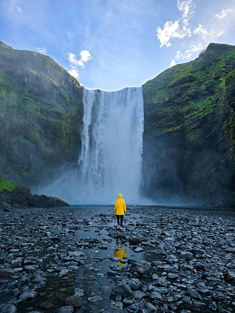 istock Waterfall marvel in Iceland with a traveler clad in yellow raincoat under a blue sky 2222411543