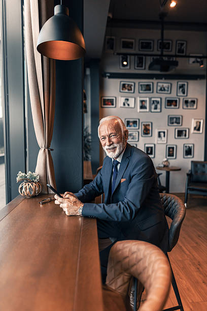 istock Mature Man in Elegant Suit Using Smartphone in Cozy Cafe 2222414442