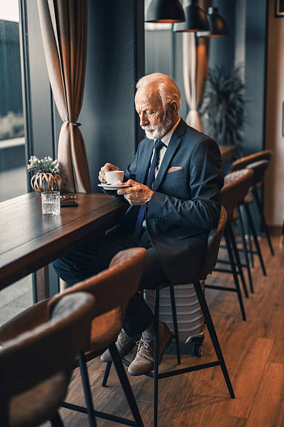 istock Elderly Man Enjoying Coffee in Cozy Modern Cafe Setup 2222414531