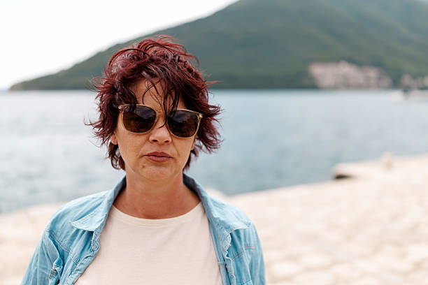 Close-up portrait of middle aged female tourist enjoying relaxed walk while exploring old coastal town