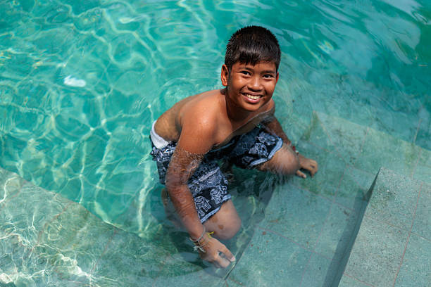 A cheerful young girl relaxing in the pool, enjoying a cool treat on a warm day, in Koh Phangan, in Thailand.