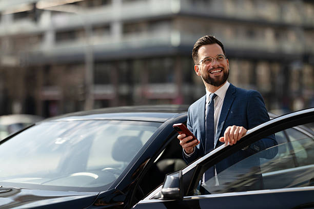 istock Businessman Checking Smartphone Beside CarDescription: 2222418672
