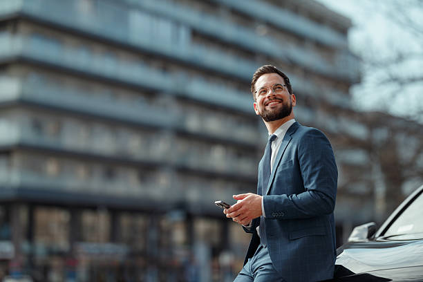 istock Businessman Checking Smartphone Beside CarDescription: 2222418675