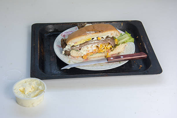 Hamburger with sausage, corn, salad and mayonaise on the table