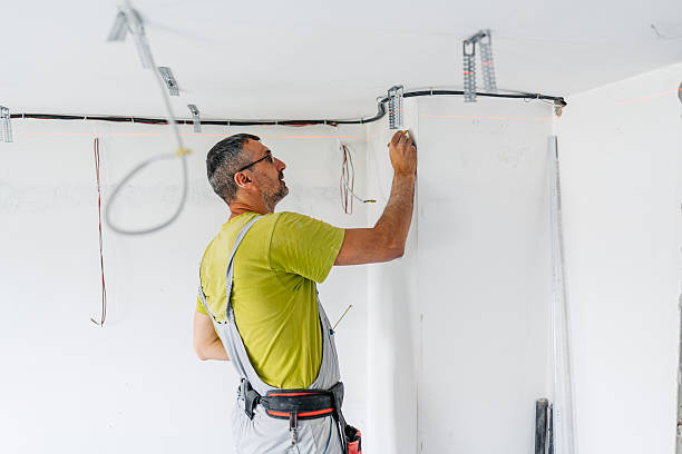 istock Mature Worker Marking The Wall With A Pen While Measuring With A Laser Before Installing Drywall On The Ceiling In An Empty Apartment Under Renovation 2222423465
