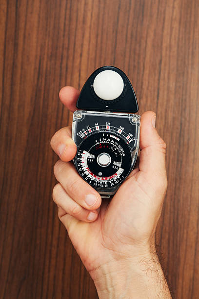istock Analog film equipment. Hand holding a vintage light meter 2222424557
