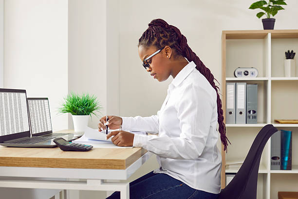 istock Female accountant working in the office, doing paperwork, and using laptop computers 2222427351
