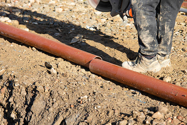 istock Builder cutting plastic drainage pipes at building site with power saw and diamond blade 2222427589
