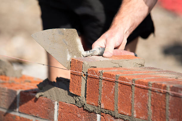 istock Close-up of Skilled worker laying bricks with trowel on construction site 2222427776