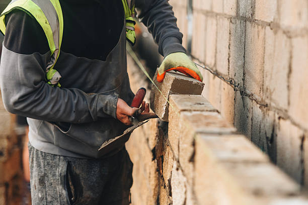 bricklayer constructing stone wall using stone blocks, cement mortar mix and trowel - murare bildbanksfoton och bilder