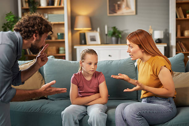 istock Sad daughter sitting on the sofa between her arguing parents at home 2222428488