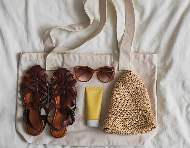 istock Braided sandals, straw hat, sunscreen, canvas bag on a light background, top view 2222429838