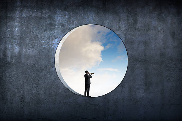 istock Man Standing In Large Circular Window Looks Through Spyglass 2222429949