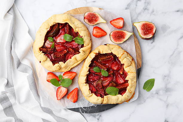 istock Tasty galettes with strawberries, figs and mint on white marble table, top view 2222433491