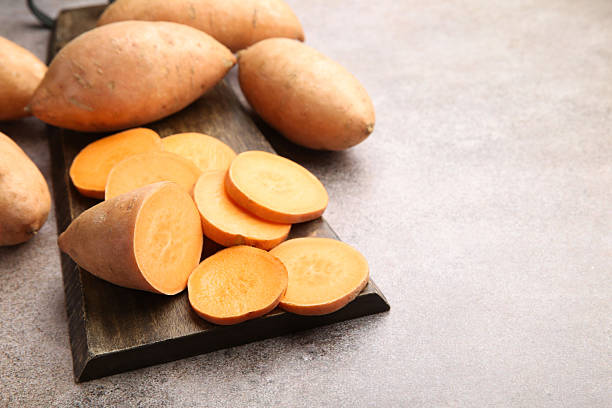 istock Fresh raw sweet potatoes on gray textured table, closeup. Space for text 2222433751
