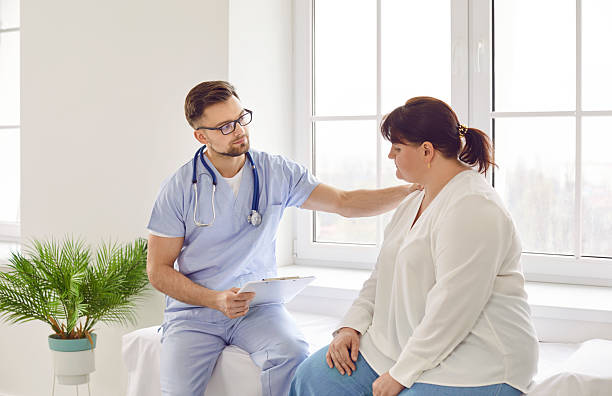 istock Doctor supporting sad fat woman, holding hand on her shoulder and expressing compassion 2222436734