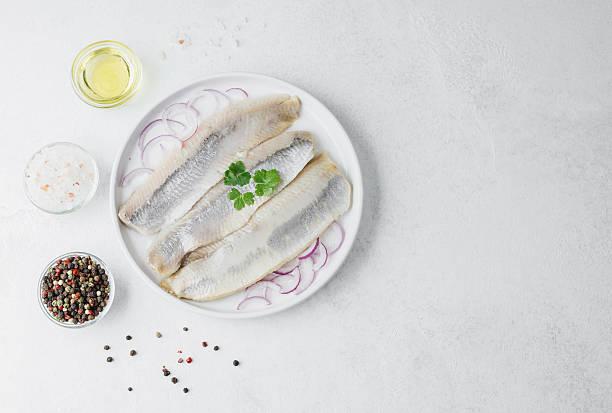 istock Marinated herring fillets with red onion, spices and herbs on white plate 2222439943
