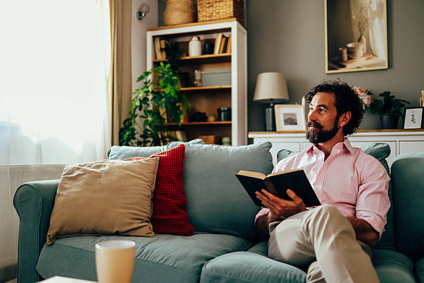istock Thoughtful man relaxing on sofa reading a book in living room 2222440531