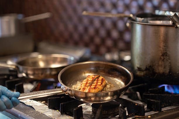 Chef is frying fish in cooking pan. High quality photo