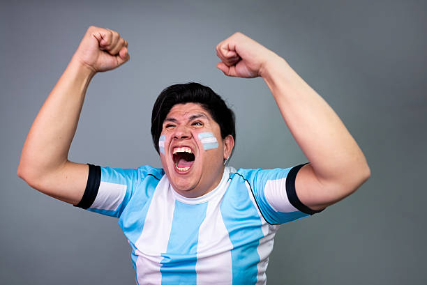 Mature gay argentinian man celebrating a goal at gray background