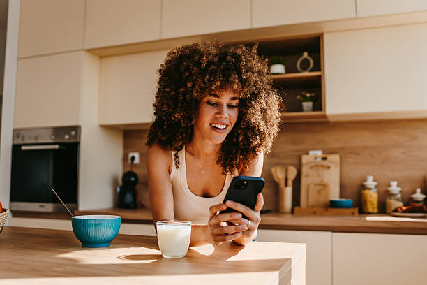 istock Young woman enjoying breakfast and browsing social media in modern kitchen 2222444217