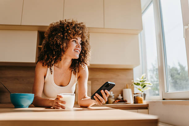 istock Young woman enjoying breakfast and browsing social media in a modern kitchen 2222444224