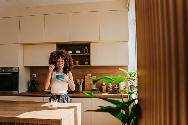 istock Happy young woman eating breakfast in modern kitchen 2222444606