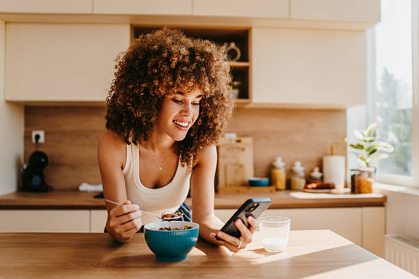 istock Young woman enjoying breakfast and browsing social media in modern kitchen 2222444630