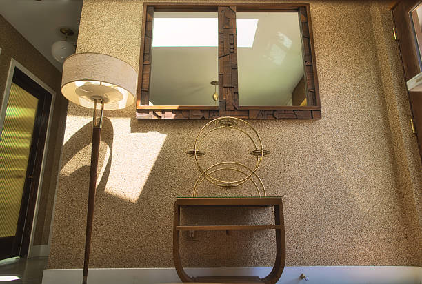 Vintage mid-century home entryway with mica wallpaper, large wall mirror, sculptural wood table, and classic floor lamp. Warm, textural, and beautifully styled.