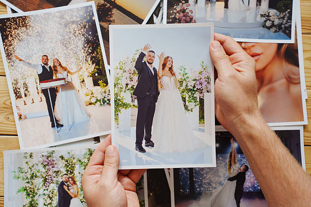 istock Men's hands put on the table and show wedding photos. 2222449733