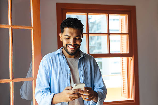 istock Smiling man using smartphone in a bright room with natural light 2222450079