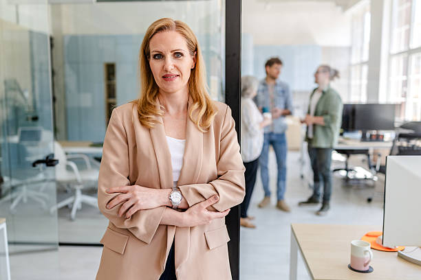 istock Confident business professional stands in modern office while colleagues engage in discussion nearby 2222453174