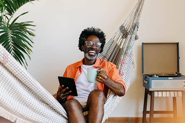 istock Happy black man relaxing in hammock with coffee and a tablet 2222453378