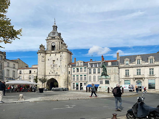 Pedestrians walking past the Grosse Horloge, a historic clock tower and former city gate marking the entrance to La Rochelle in France. September 2022