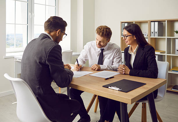 istock Confident business man signing some documents at the office reaching agreement with partners. 2222459801