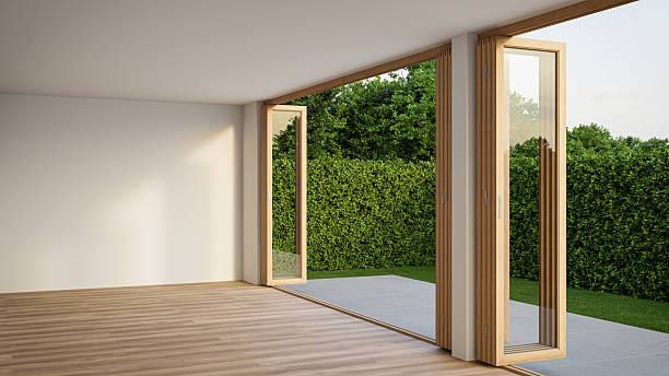 istock Empty white room with wood-framed glass doors open to garden. 2222462003