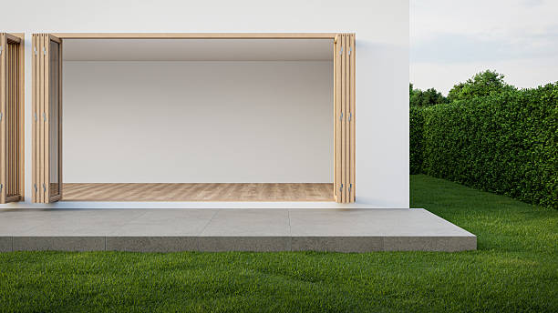 istock Empty white room with wood-framed glass doors open to garden. 2222462009