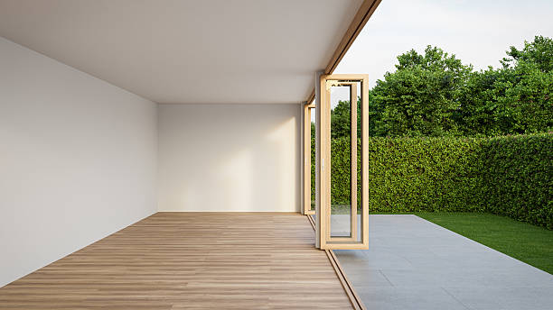 istock Empty white room with wood-framed glass doors open to garden. 2222462014