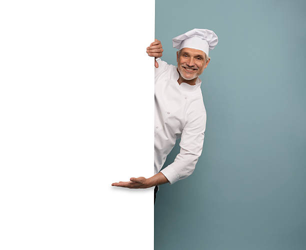 istock Mature male chef presenting something over blue background. 2222466328