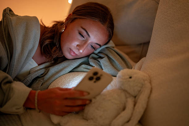 Young Woman Relaxing on Sofa Using Smartphone in Cozy Light Setting