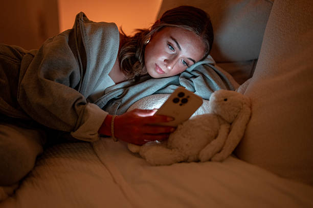 istock Woman Lying On Sofa Browsing Smartphone In Cozy Evening Atmosphere 2222468235